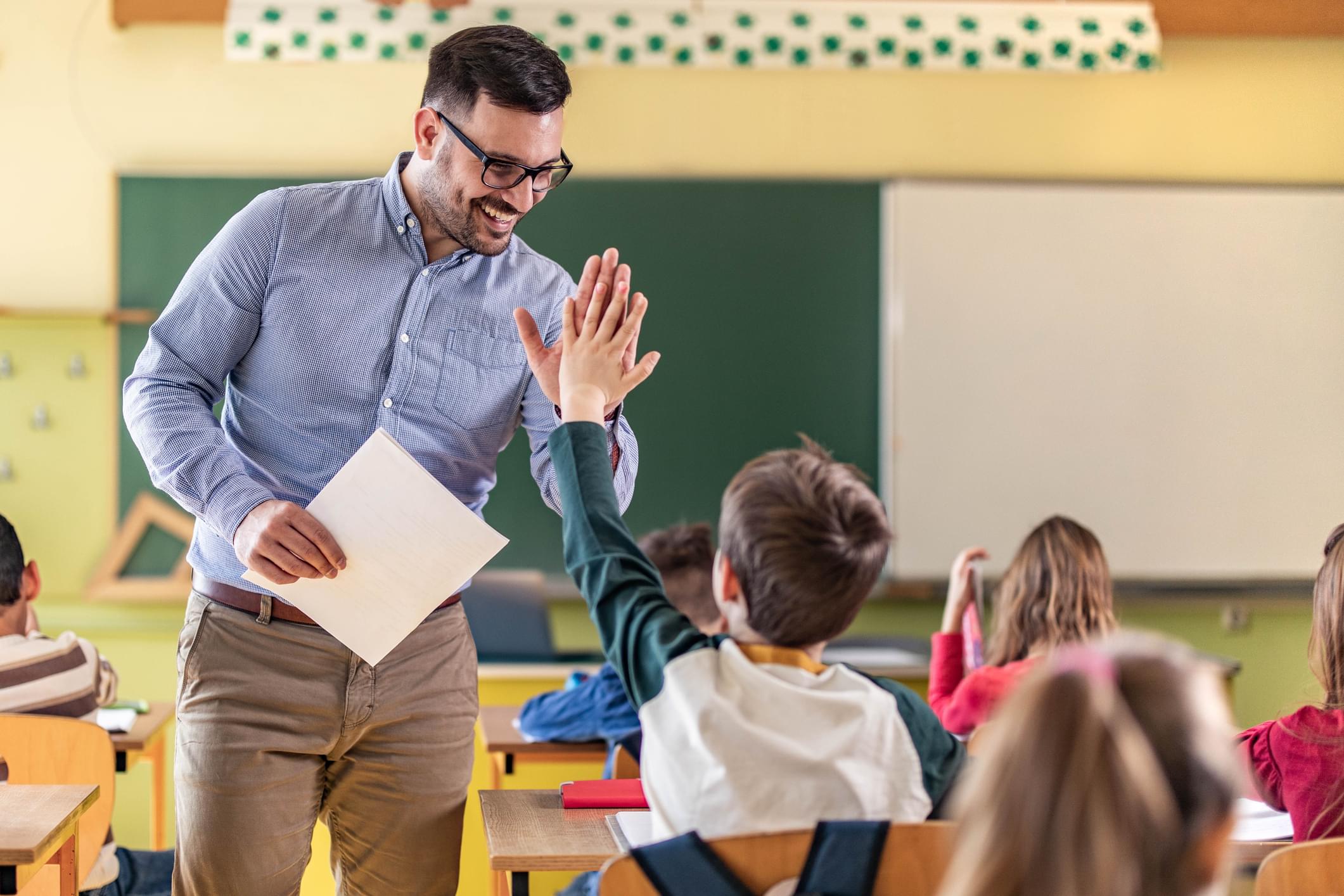 Teacher and student high fiving in classroom