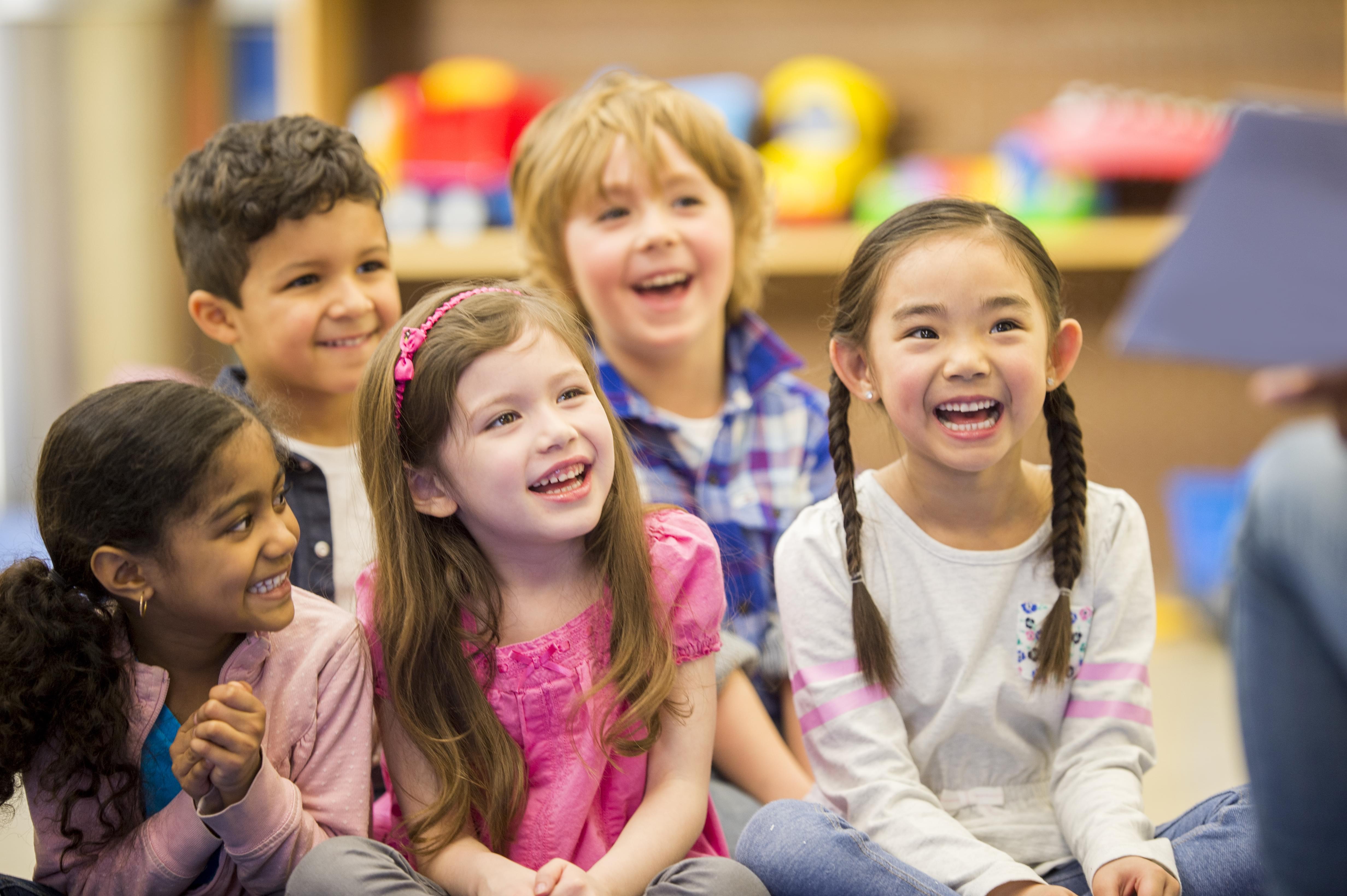 A group of students sitting on the mat looking engaged as their teacher teaches